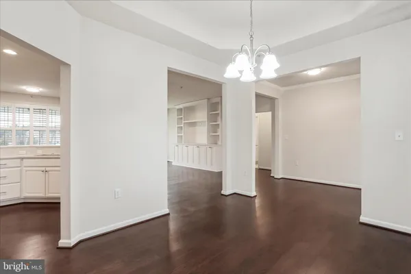 an empty room with wooden floor chandelier and windows