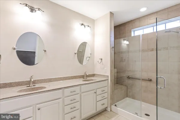 a bathroom with a double vanity sink mirror and shower