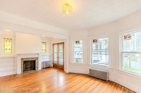 wooden floor fireplace and windows in an empty room