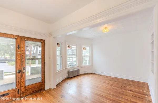 a view of an empty room with wooden floor and a window