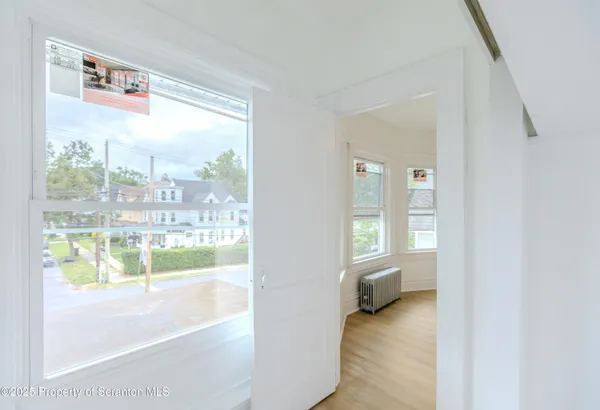 a view of an empty room with window and wooden floor