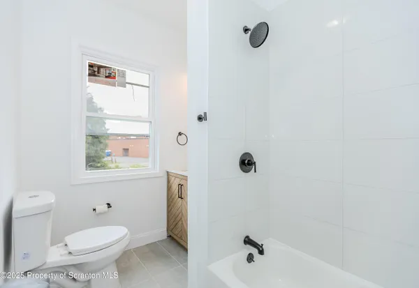 a bathroom with a shower a toilet and a window