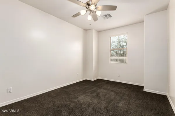 an empty room with a window and a fan