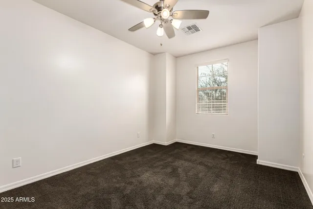 an empty room with a window and a fan