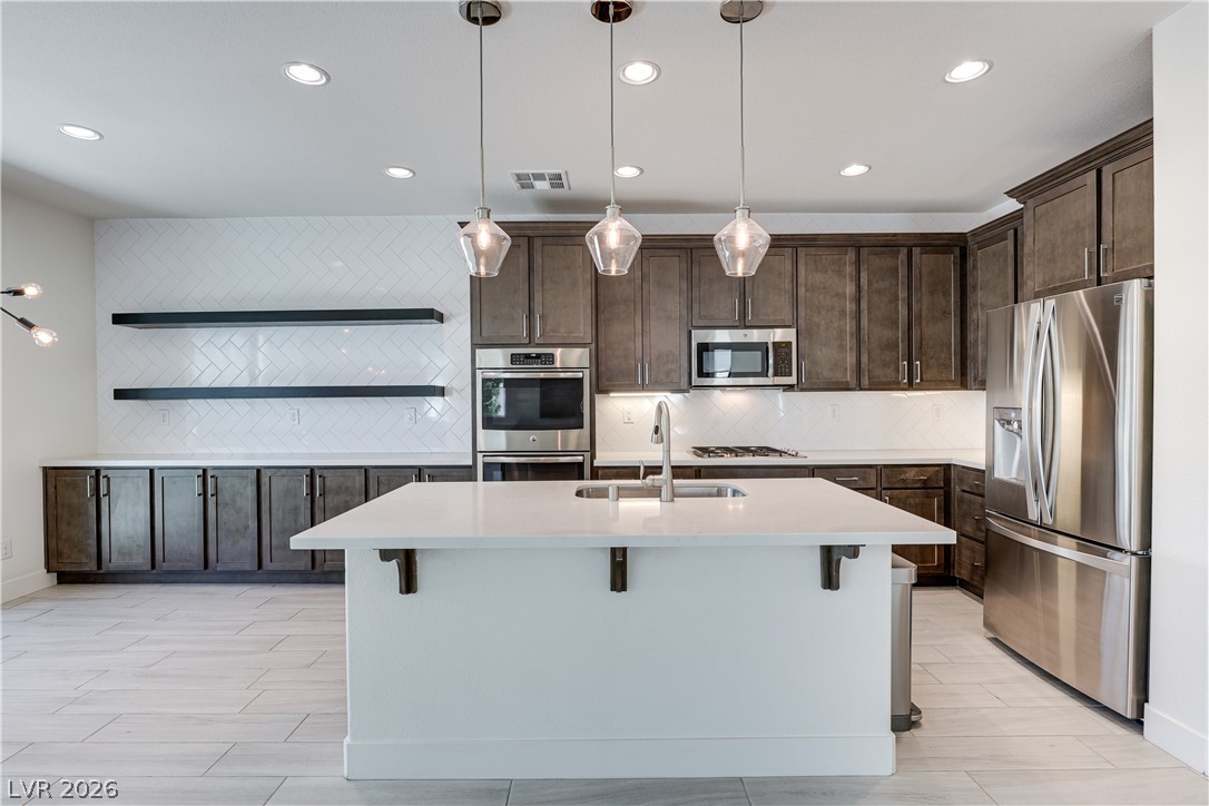 5954 Smith Valley Road Las Vegas, NV 89148 - Photo 1 of 23 Modern kitchen with sleek dark cabinetry, bright white countertops, and a full suite of stainless steel appliances.