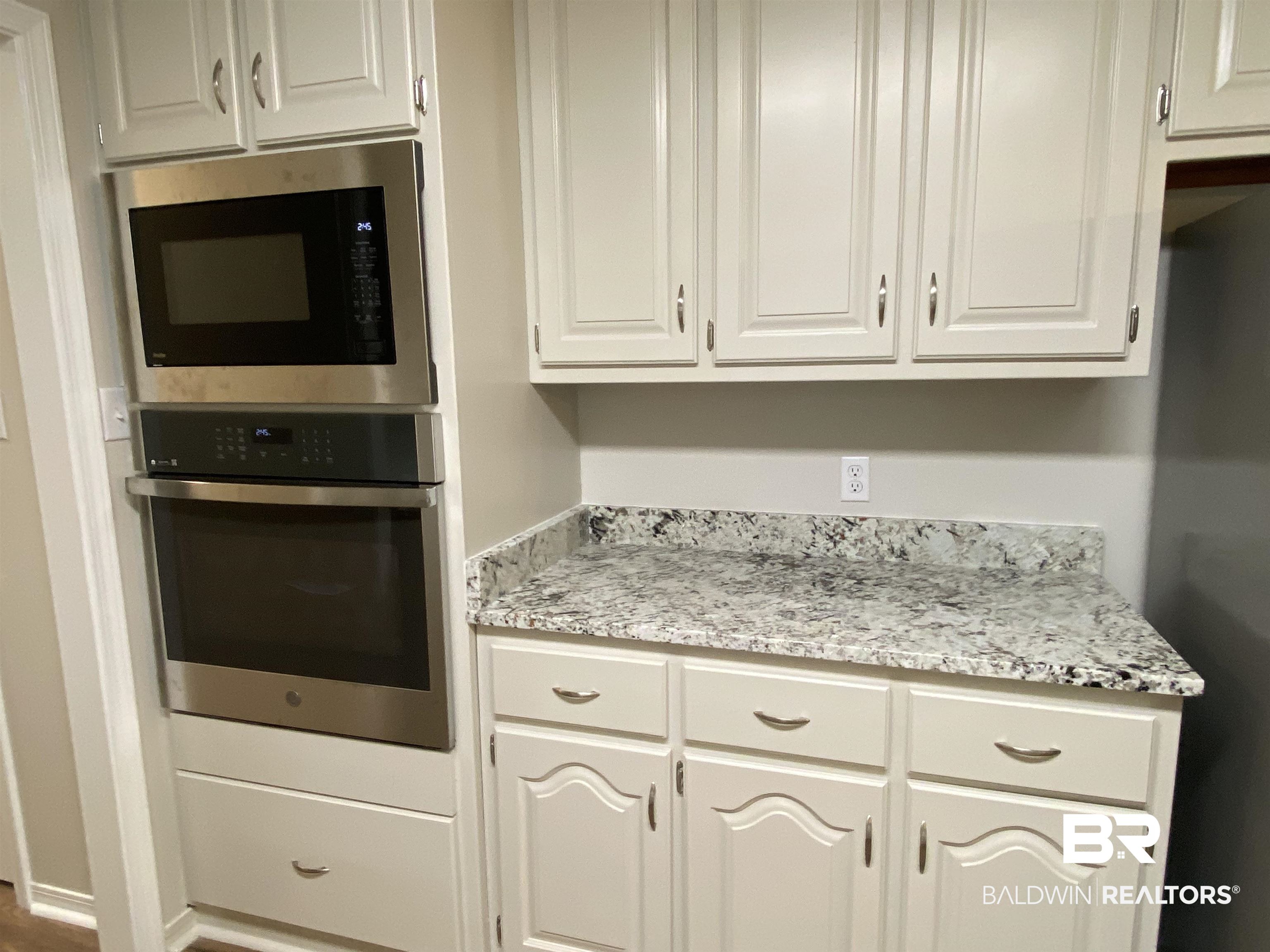 12150 Lee Bishop Road Irvington, AL 36544 - Photo 12 of 26 Kitchen with light stone counters, white cabinets, stainless steel oven, and built in microwave