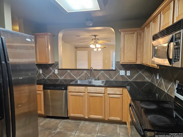a kitchen with granite countertop a refrigerator and a stove top oven