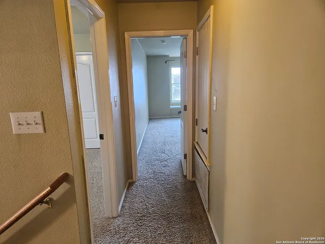 an empty room with a chandelier fan and windows