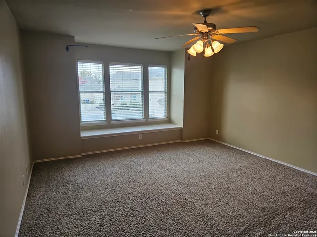 a view of an empty room with a chandelier fan