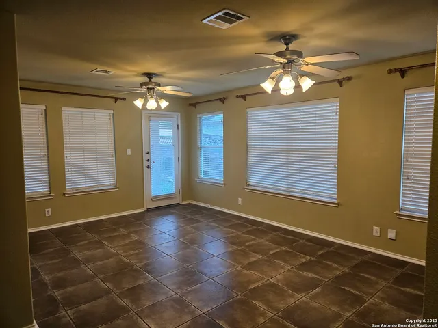 a view of an empty room with window and chandelier fan