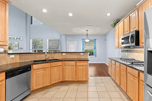 a large kitchen with stainless steel appliances granite countertop a sink and cabinets