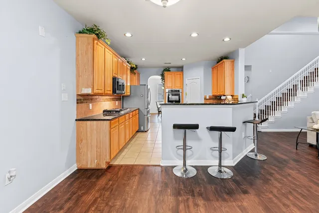 a kitchen with stainless steel appliances a kitchen island hardwood floor sink stove dining table and chairs