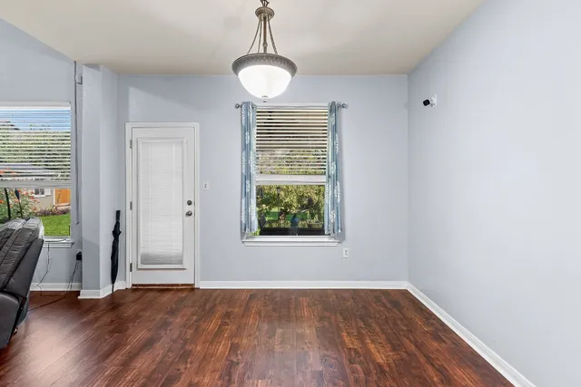 a view of an empty room with wooden floor and a window