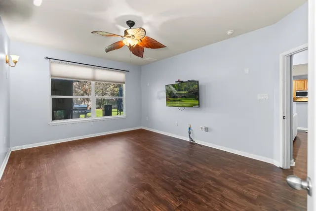 a view of an empty room with window and wooden floor
