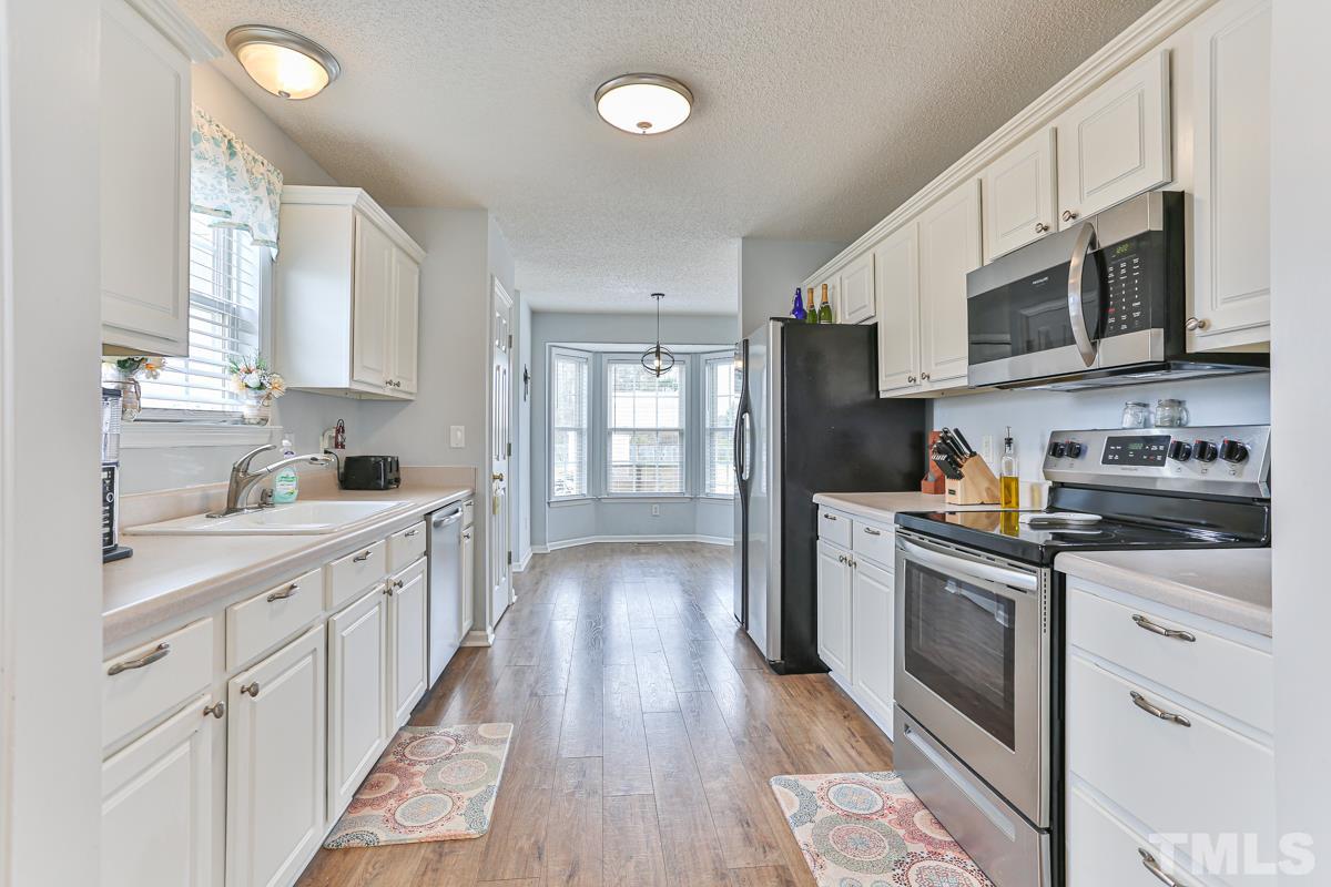 243 Rosa Circle Willow Spring, NC 27592 - Photo 4 of 28 a kitchen with stainless steel appliances granite countertop a refrigerator oven a sink dishwasher and white cabinets with wooden floor