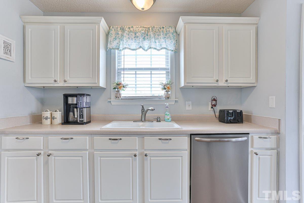 243 Rosa Circle Willow Spring, NC 27592 - Photo 8 of 28 a kitchen with granite countertop white cabinets and window