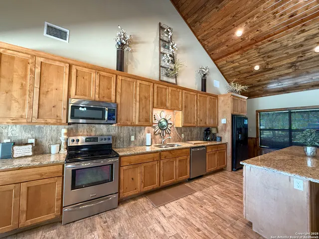 a kitchen with stainless steel appliances kitchen island granite countertop a stove sink and cabinets
