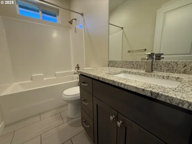 a bathroom with a granite countertop bathtub sink vanity mirror and toilet