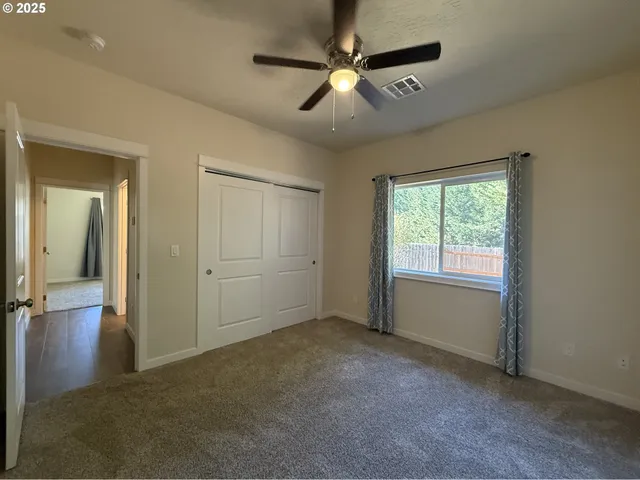 a view of empty room with window and ceiling fan
