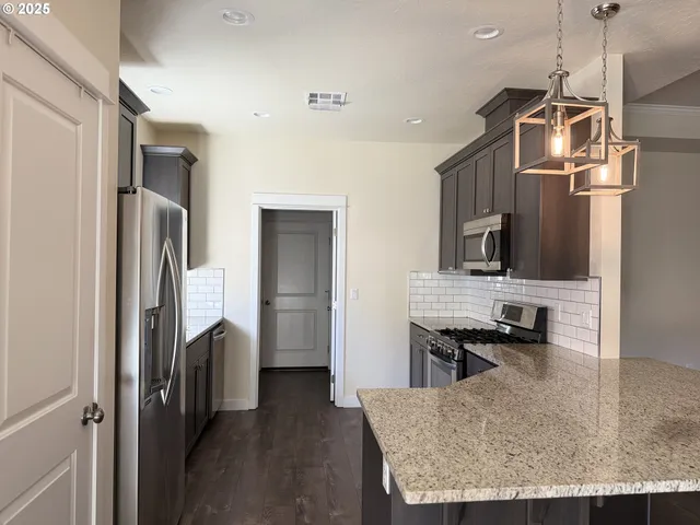 a kitchen with stainless steel appliances granite countertop a refrigerator a stove and a sink