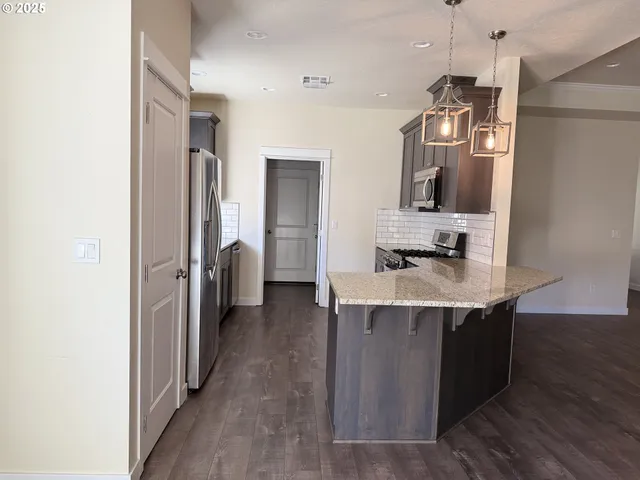 a kitchen with stainless steel appliances granite countertop a refrigerator a sink dishwasher and a stove with wooden floor