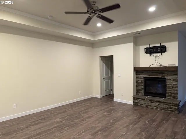 a view of an empty room with wooden floor fireplace and a window