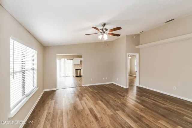 a view of empty room with wooden floor and fan