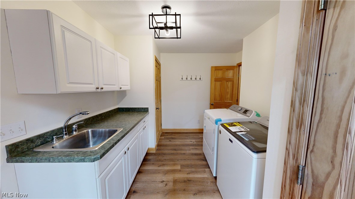 15548 Trask Road Thompson, OH 44086 - Photo 13 of 31 Laundry room, white cabinets, independent washer and dryer, pendant lighting, and sink