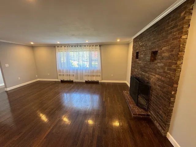 an empty room with wooden floor and fireplace