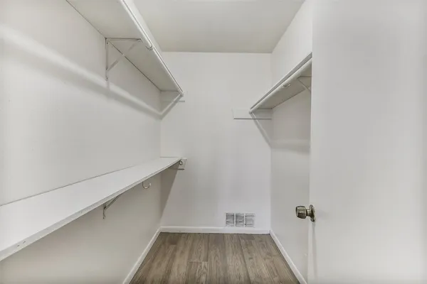 a view of walk in closet with wooden floor