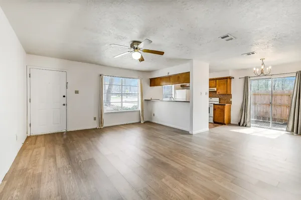 a view of an empty room with a window and wooden floor