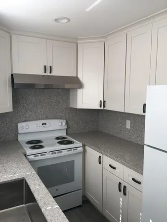 a kitchen with granite countertop white cabinets and white stove