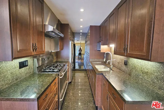 a kitchen with stainless steel appliances granite countertop a sink stove and refrigerator