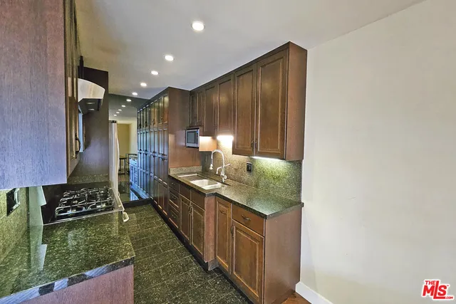 a kitchen with kitchen island granite countertop a stove and a sink