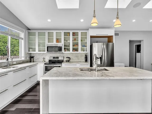 a kitchen with stainless steel appliances kitchen island granite countertop a refrigerator and a sink