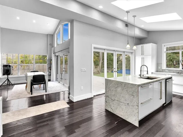 a living room with stainless steel appliances granite countertop hardwood floor and a large window