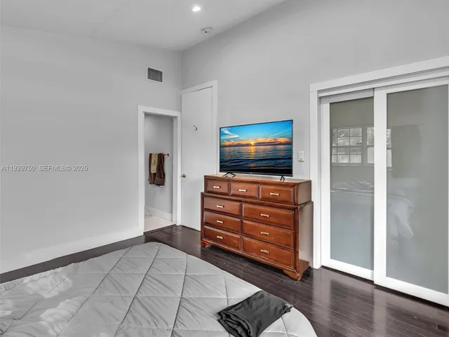 a room with a flat screen tv on dresser and a window