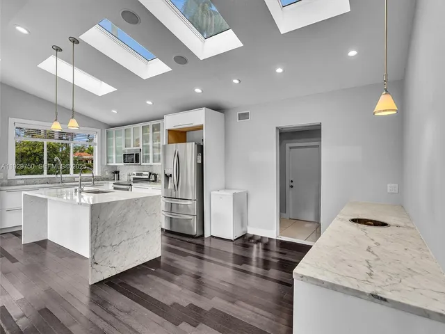 a kitchen with stainless steel appliances granite countertop a refrigerator a sink and a stove