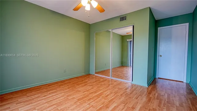 a view of a room with wooden floor a fan and a window