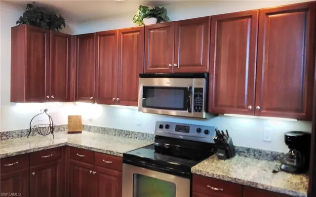 a kitchen with granite countertop wooden cabinets and a stove top oven