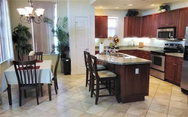 a kitchen with granite countertop a table chairs and microwave