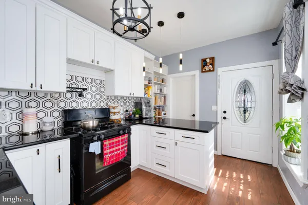 a kitchen with granite countertop a sink a stove cabinets and wooden floor