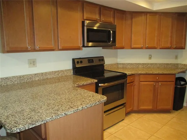 a kitchen with granite countertop wooden cabinets and a stove top oven