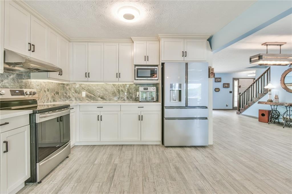 591 Rue Cezzan Lavonia, GA 30553 - Photo 8 of 36 a kitchen with stainless steel appliances white cabinets and wooden floors
