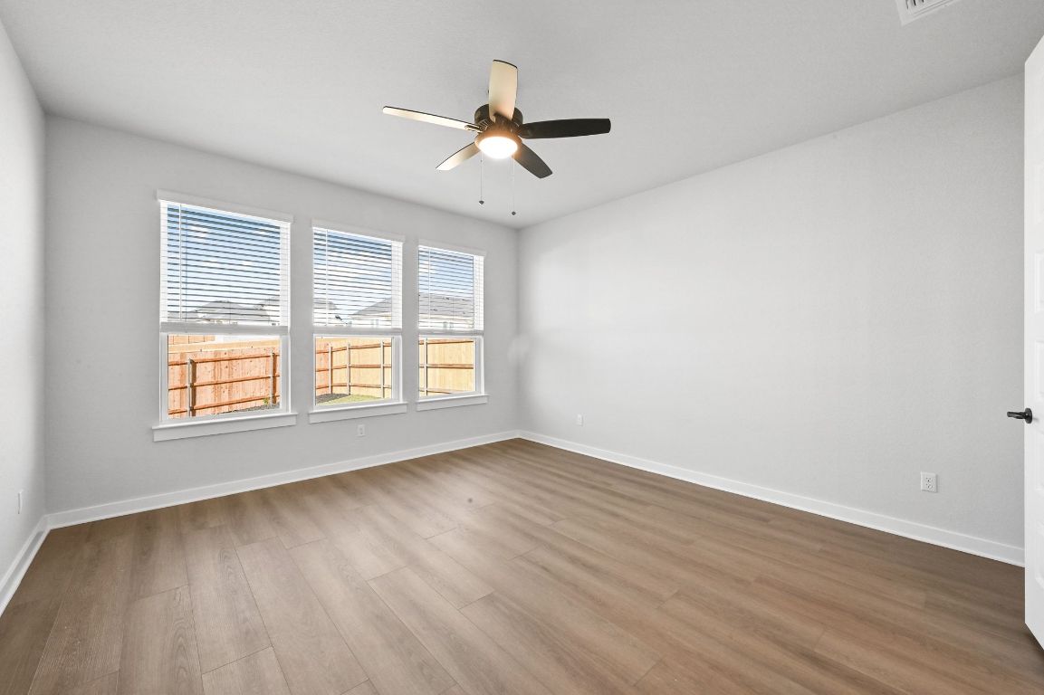144 Granit Oak Drive Dripping Springs, TX 78620 - Photo 11 of 33 an empty room with wooden floor ceiling fan and windows