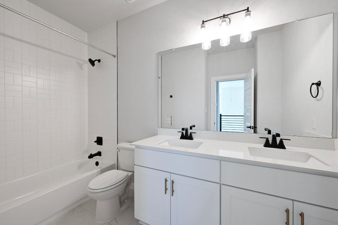 144 Granit Oak Drive Dripping Springs, TX 78620 - Photo 22 of 33 a bathroom with a toilet a sink a tub and mirror