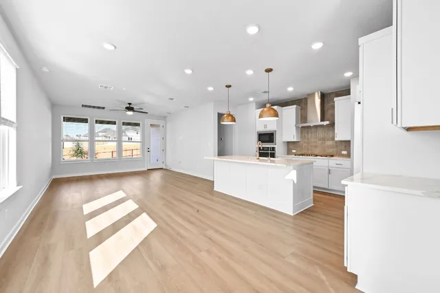a large kitchen with kitchen island a sink dishwasher stove and white cabinets with wooden floor