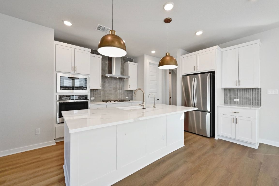 144 Granit Oak Drive Dripping Springs, TX 78620 - Photo 5 of 33 a kitchen with stainless steel appliances granite countertop a sink a stove a refrigerator and island with wooden floor