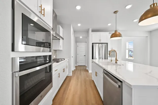 a large kitchen with stainless steel appliances granite countertop a sink a stove and a wooden floors