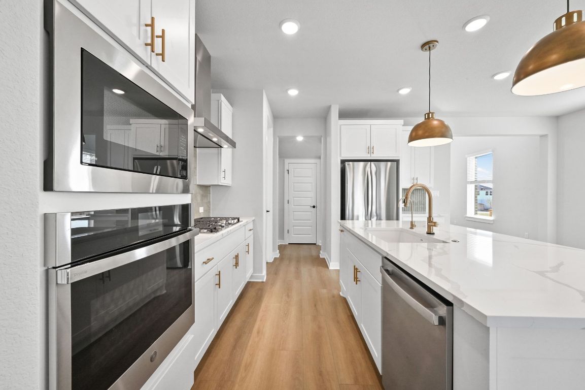 144 Granit Oak Drive Dripping Springs, TX 78620 - Photo 6 of 33 a large kitchen with stainless steel appliances granite countertop a sink a stove and a wooden floors
